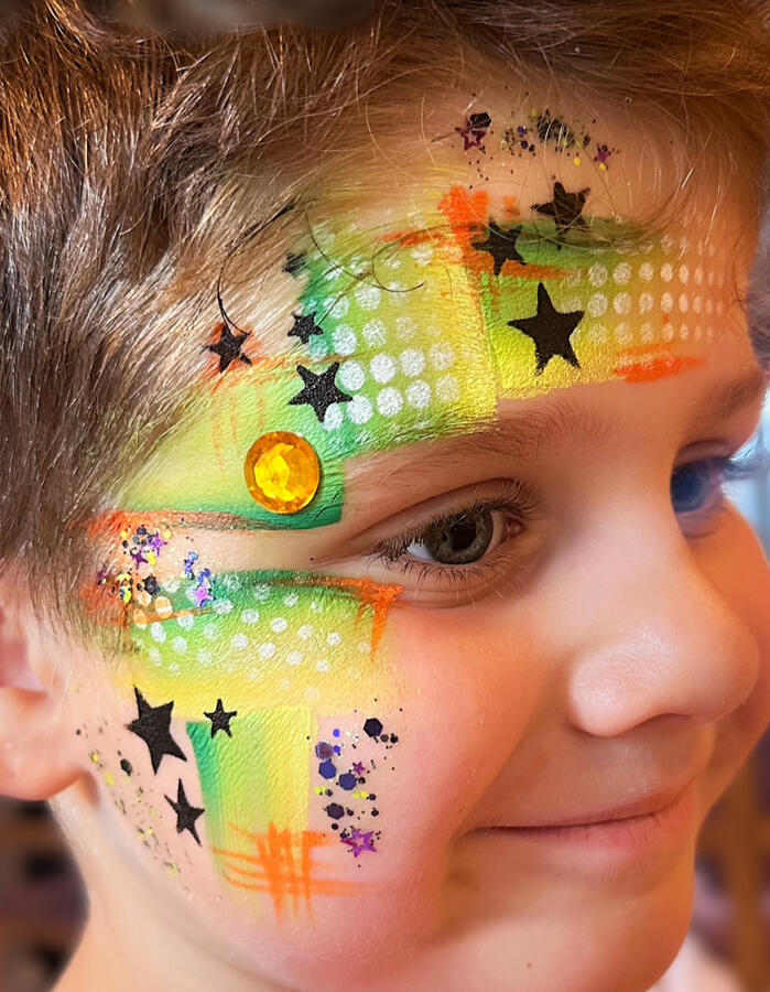 Abstract face paint design with festival glitter
